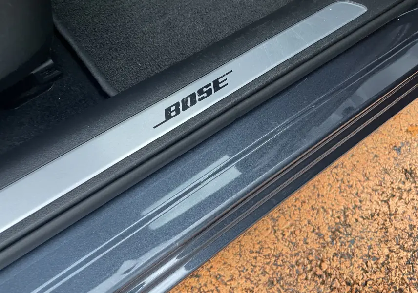 Gros plan sur la plaque de seuil de porte avec logo BOSE sur un Renault Kadjar gris titanium, intérieur côté conducteur.
