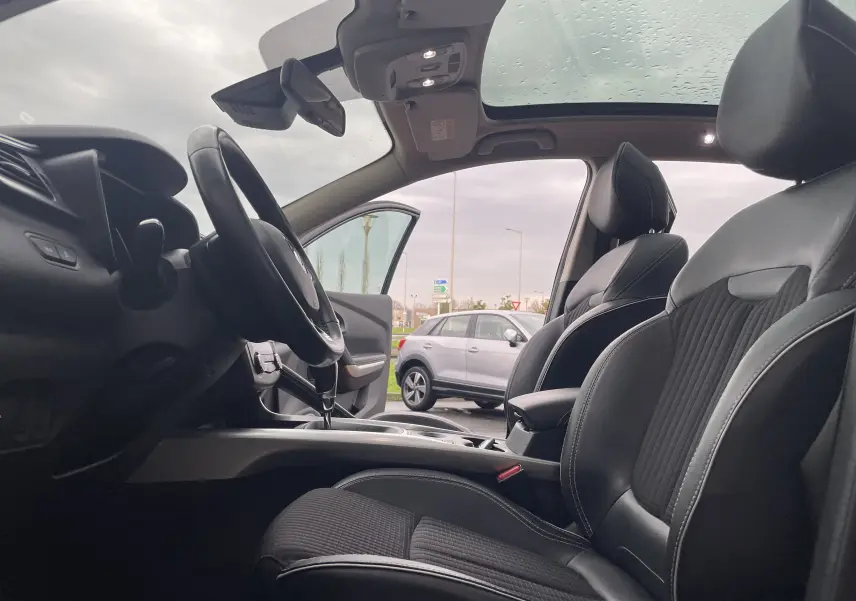 Vue intérieure côté conducteur du Renault Kadjar 2018, sièges en tissu noir et toit panoramique visible.