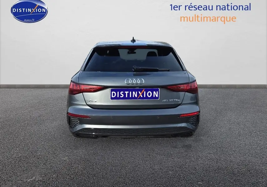 Vue arrière d'une Audi A3 Sportback 45 TFSI e gris Daytona avec feux LED et logo distinctif sur fond neutre.