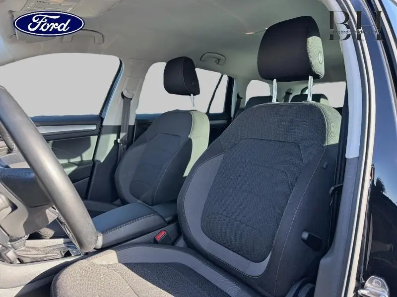 Vue intérieure côté conducteur du Skoda Kodiaq noir Magic Nacré, sièges tissu noir et gris avec accoudoir central cuir.