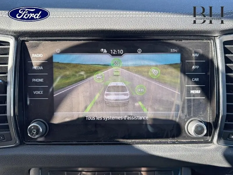 Écran tactile central affichant l'aide à la conduite avec vue arrière d'une route, intérieur Ford noir.