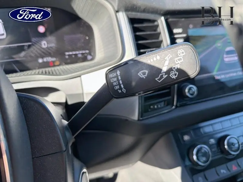 Levier de commande des essuie-glaces en gros plan à gauche du volant dans l'habitacle d'un Skoda Kodiaq noir Magic Nacré.