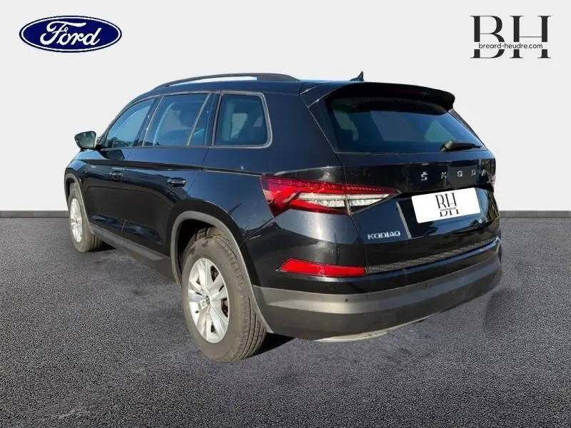 Vue 3/4 arrière droite d'un Skoda Kodiaq noir Magic Nacré 7 places avec feux arrière LED et barres de toit visibles.