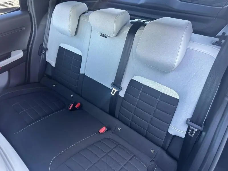 Vue intérieure arrière de la banquette bicolore noir et gris clair du Citroën C3 1.2 Turbo 2025 avec ceintures et appuie-têtes.