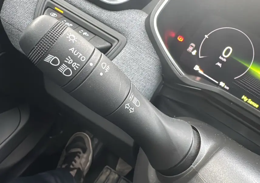 Gros plan sur la commande des feux et clignotants dans l’habitacle gris de la Renault Clio V TCe 90 Techno Plus 2025.