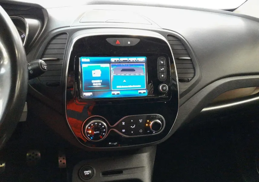 Vue intérieure centrée sur la console centrale du Renault Captur TCe 120 Energy Iridium avec écran tactile et commandes de climatisation.