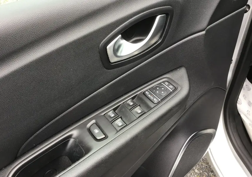 Gros plan sur la porte avant gauche noire du Renault Captur 2017, montrant les commandes électriques des vitres et la poignée argentée.