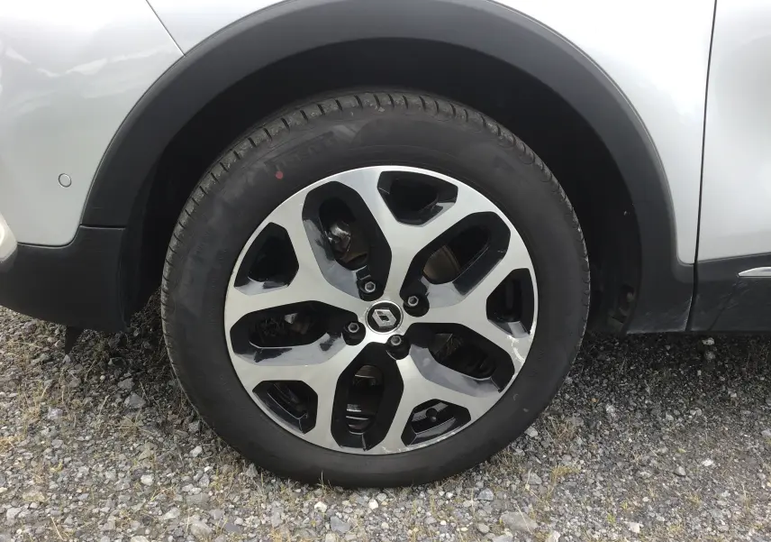 Gros plan sur la roue avant gauche d’un Renault Captur gris clair métal avec jante alliage bicolore noire et argent.