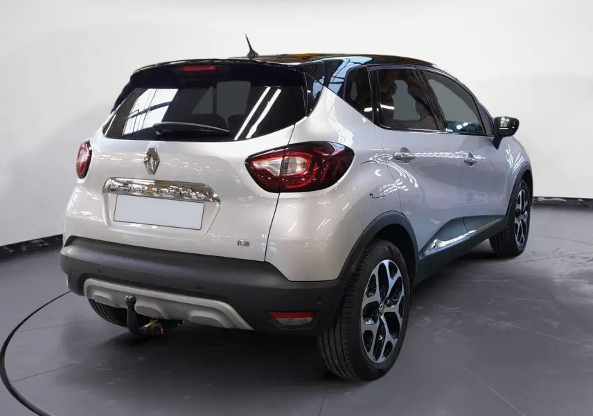 Vue 3/4 arrière droite d'un Renault Captur TCE 120 Energy Iridium gris clair métallisé avec toit noir et jantes alliage 17 pouces.