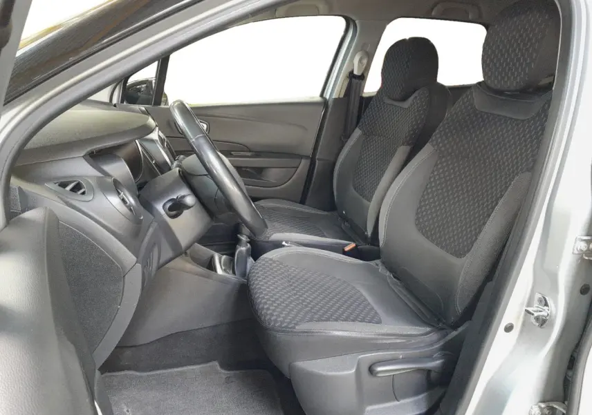 Vue intérieure côté conducteur du Renault Captur gris clair, montrant les sièges avant en tissu noir et la console centrale.