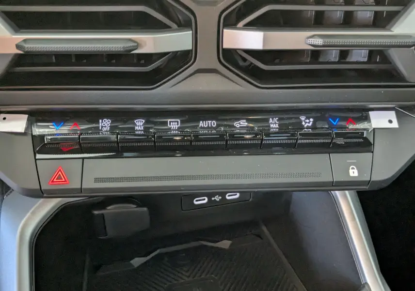 Vue rapprochée de la console centrale du Dacia Bigster Hybrid 155 Journey 2026, montrant les commandes de climatisation et les ports USB.