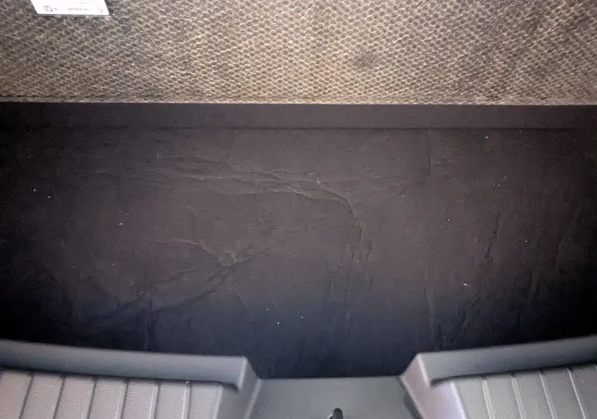 Vue intérieure du coffre du Dacia Bigster Hybrid 155 Journey 2026, montrant le tapis de sol noir et les bordures grises.