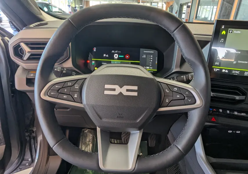 Vue centrée sur le volant du Dacia Bigster Hybrid 155 Journey avec tableau de bord numérique et écran tactile multimédia.