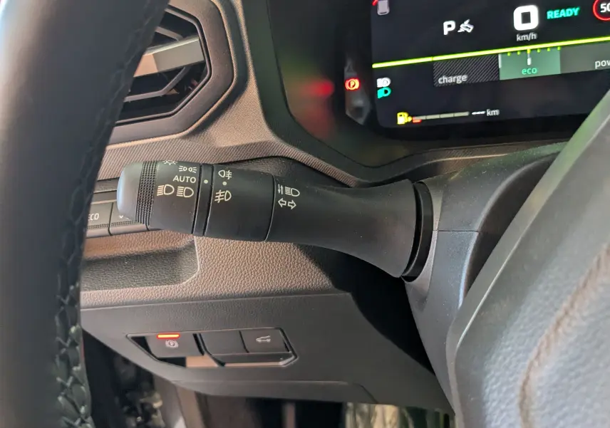 Gros plan sur la manette de clignotants à gauche du volant dans l'habitacle du Dacia Bigster Hybrid 155 gris schiste.
