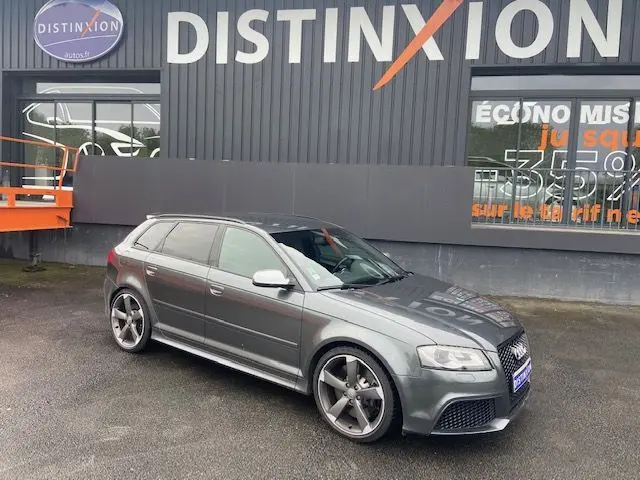 Audi RS3 Sportback gris Daytona vue 3/4 avant côté gauche, avec jantes alliage et calandre noire distinctive.