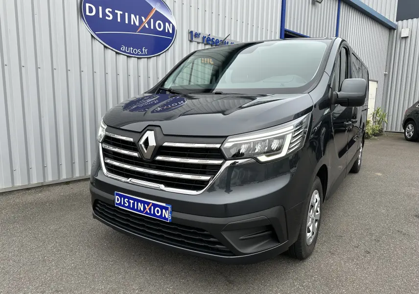 Renault Trafic Combi gris Comète en 3/4 avant droit, avec calandre chromée et phares LED allumés.