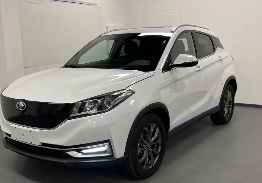 Vue 3/4 avant du SUV électrique blanc SERES 3 Luxury avec calandre noire lisse et jantes foncées dans un garage.