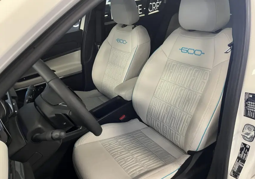 Vue intérieure côté conducteur du FIAT 600 blanc 2024, sièges ivoire avec logo 600 bleu et surpiqûres FIAT.
