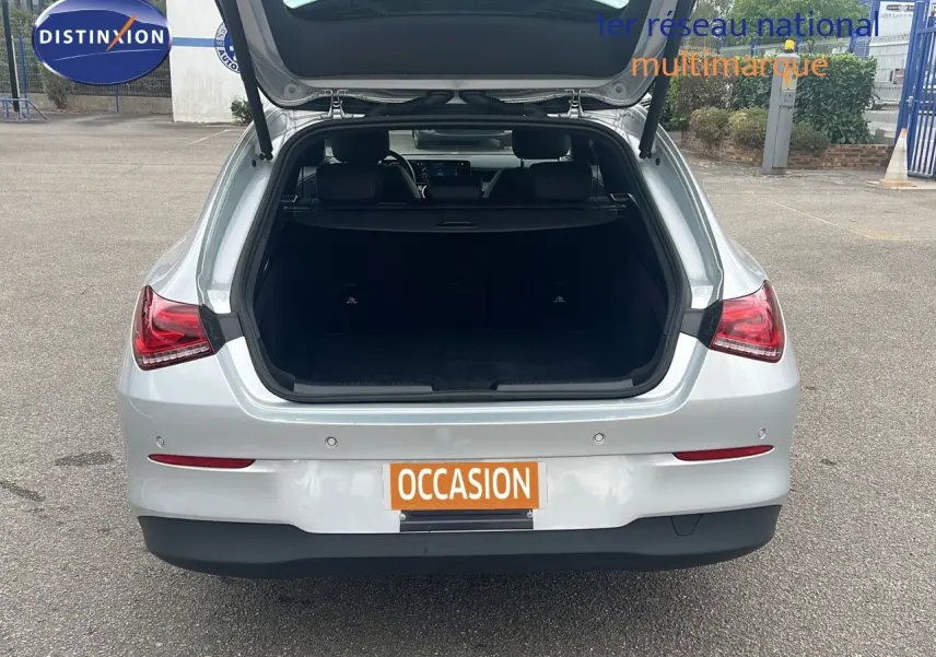 Vue arrière d'une Mercedes Classe CLA Shooting Brake 180 argent iridium avec coffre ouvert en extérieur.
