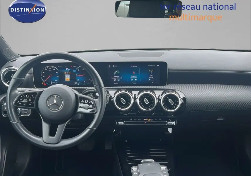 Tableau de bord et volant noir d'une Mercedes Classe CLA Shooting Brake 180 Diesel, avec écran digital large et aérateurs ronds.