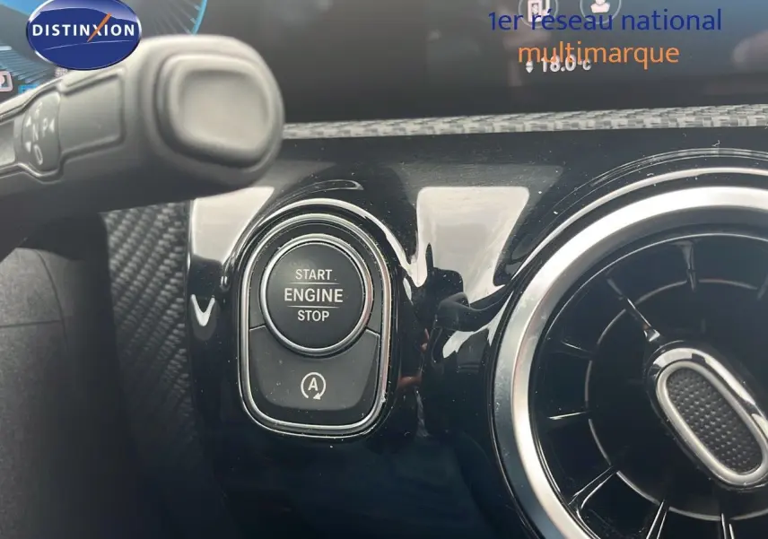 Bouton start/stop moteur et aérateur rond sur tableau de bord noir brillant d'une Mercedes Classe CLA Shooting Brake argent iridium.