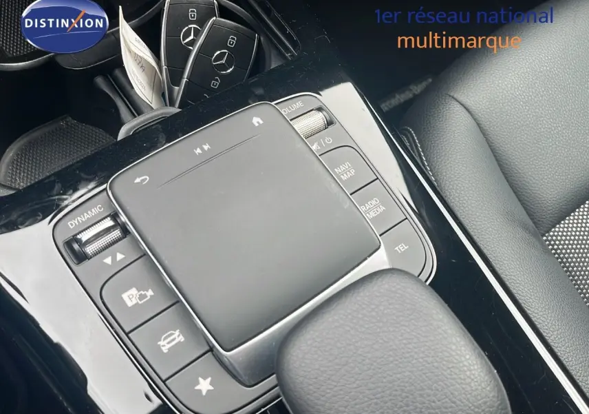 Vue rapprochée de la console centrale noire et des clés Mercedes posées sur un siège en cuir gris du CLA Shooting Brake argent.