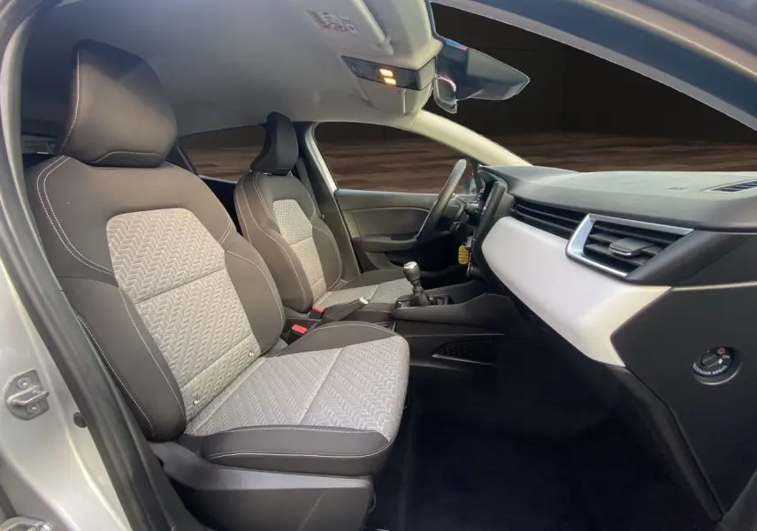 Vue intérieure côté passager de la Renault Clio V 2023 avec sellerie beige et tableau de bord gris clair.