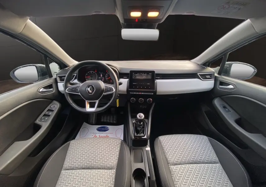 Vue intérieure avant de la Renault Clio V TCE 90 Evolution, sellerie beige et tableau de bord avec écran tactile central.