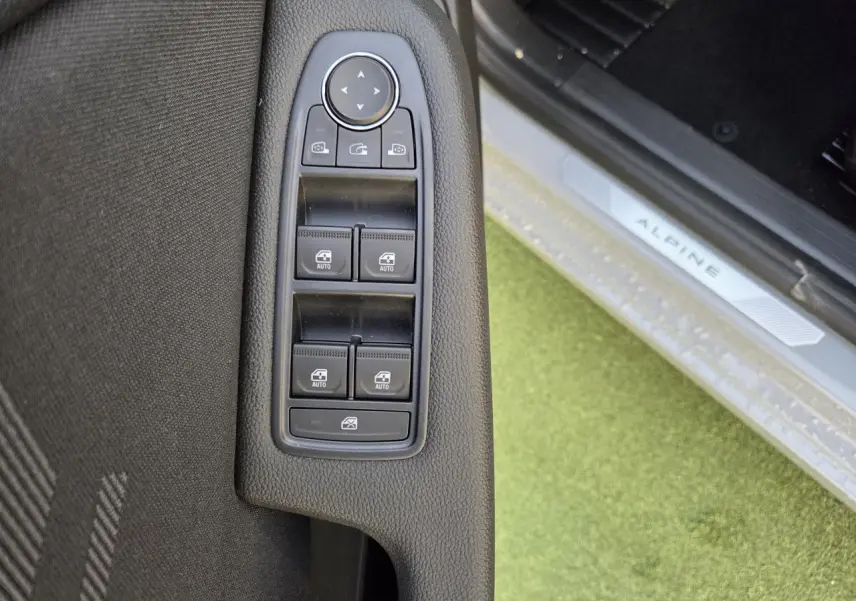 Gros plan sur les commandes des vitres et rétroviseurs côté gauche, seuil de porte Alpine visible sur Renault Clio Gris Rafale.
