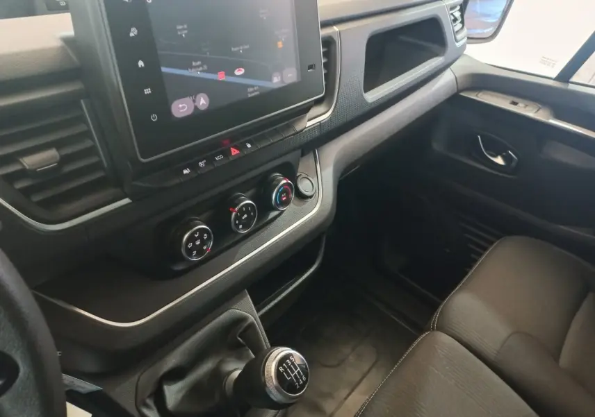 Vue intérieure côté passager du tableau de bord et levier de vitesses manuel du Renault Trafic Fourgon blanc 2022.