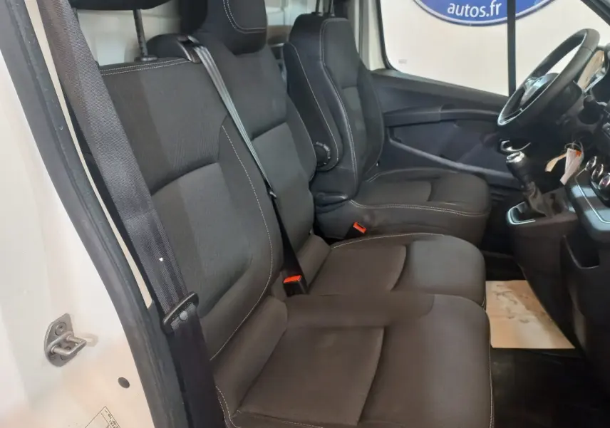 Vue intérieure côté conducteur du Renault Trafic Fourgon 2022, sièges noirs et volant multifonctions visible.