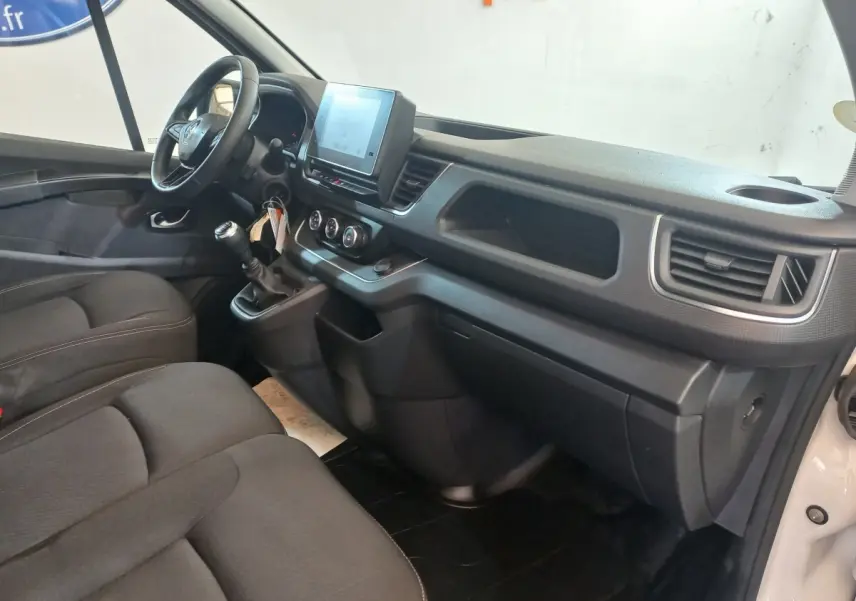 Vue intérieure côté conducteur du Renault Trafic Fourgon blanc 2022, tableau de bord avec écran tactile et volant multifonctions.