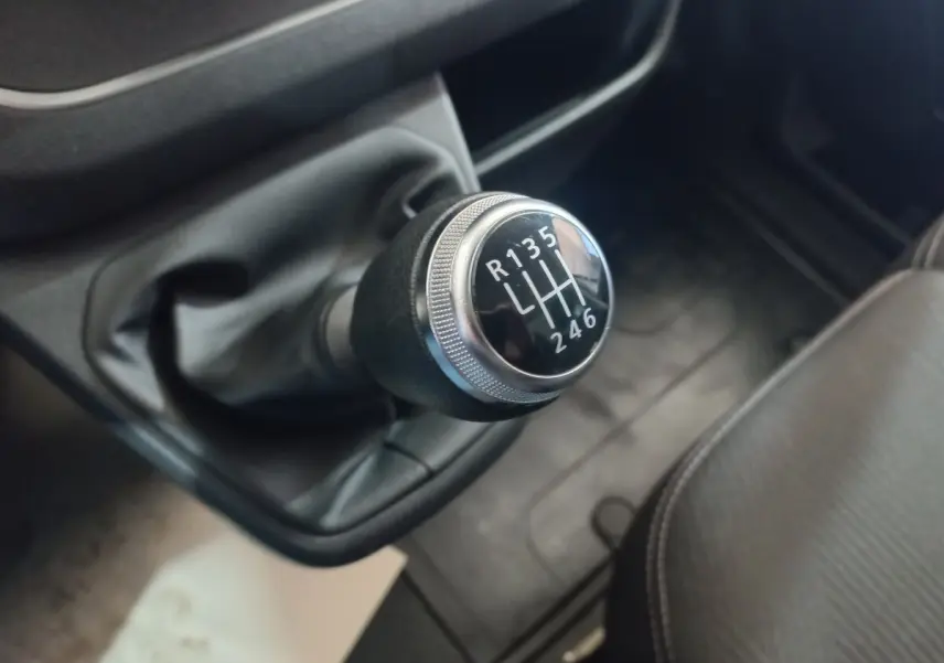 Gros plan sur le levier de vitesses manuel noir et chrome du Renault Trafic Fourgon blanc, intérieur côté conducteur.