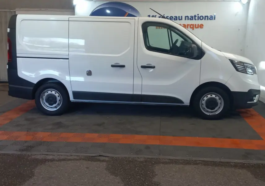 Vue de profil côté gauche d’un Renault Trafic Fourgon blanc, version utilitaire avec portes latérales pleines.
