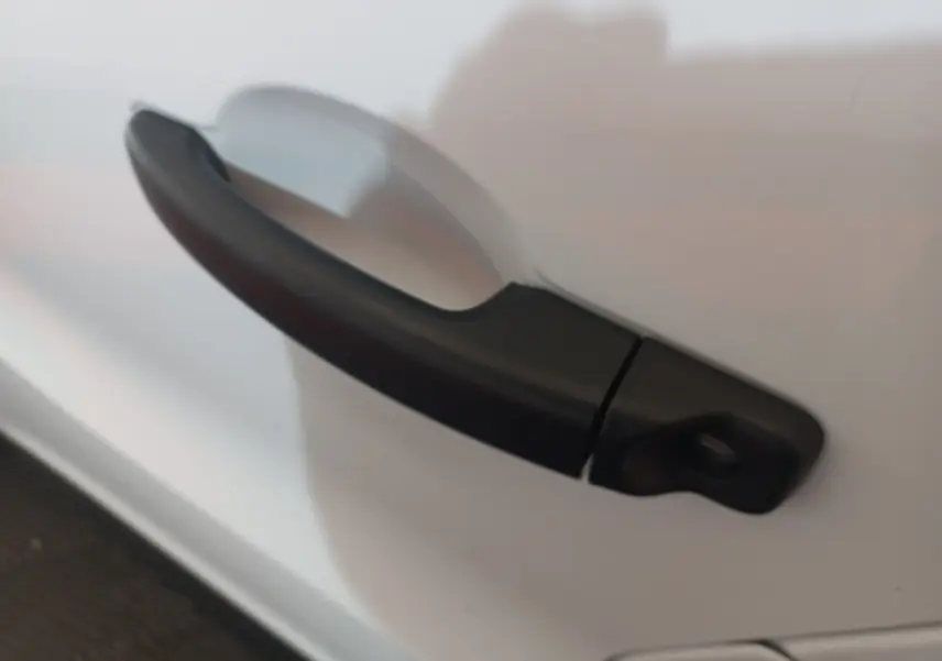 Poignée de porte noire en gros plan sur la portière blanche d’un Renault Trafic Fourgon 2022.