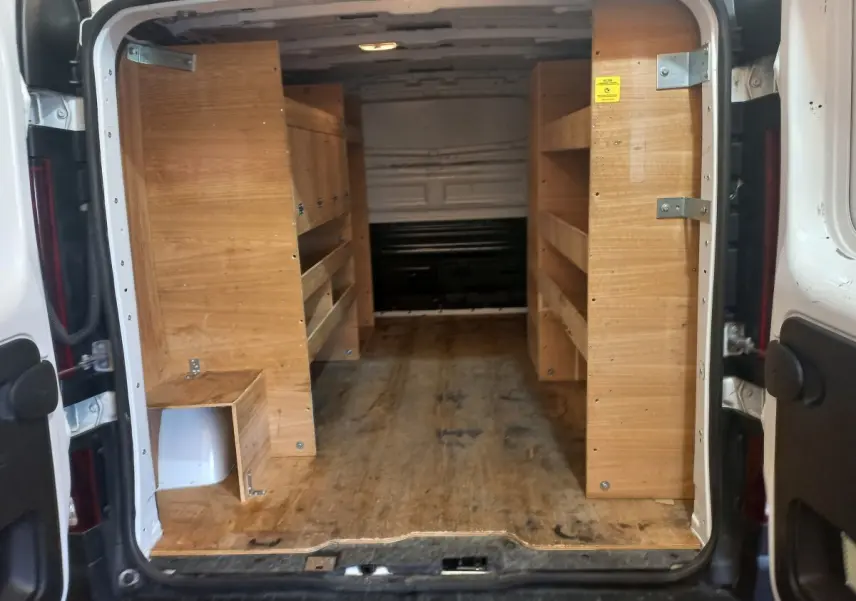 Vue arrière ouverte du Renault Trafic Fourgon blanc de 2022, montrant l'intérieur équipé de rangements en bois.