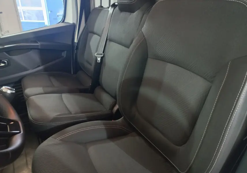 Vue intérieure côté droit des sièges avant noirs du Renault Trafic Fourgon blanc, avec ceinture de sécurité visible.