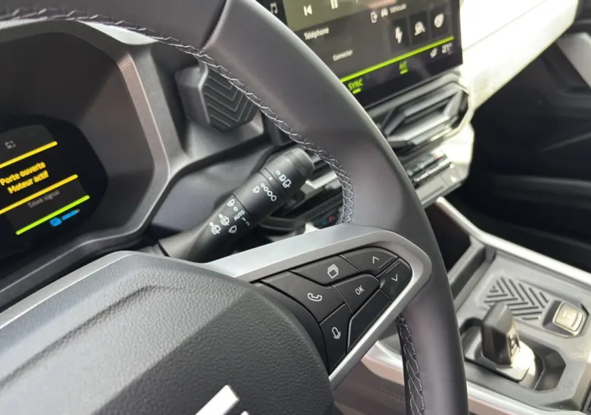 Gros plan sur le volant cuir et la console centrale du Dacia Bigster Hybrid 155 Journey Plus, intérieur moderne noir et gris.