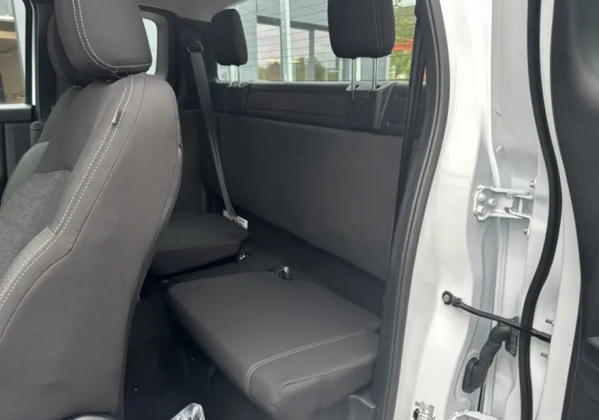 Vue intérieure côté droit du Ford Ranger blanc glacier 2025, montrant la banquette arrière rabattue et les sièges avant en tissu noir.