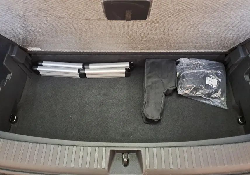 Coffre ouvert d'un Skoda Kodiaq gris graphite, vue de dessus montrant un rangement avec accessoires pliés.