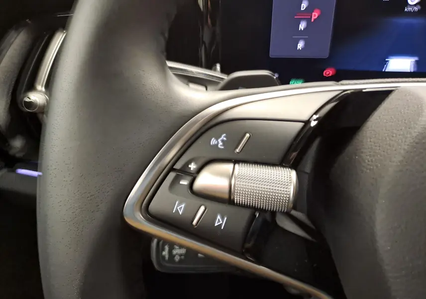 Gros plan sur les commandes au volant du Skoda Kodiaq 2025, avec molette métallique et affichage digital en arrière-plan.