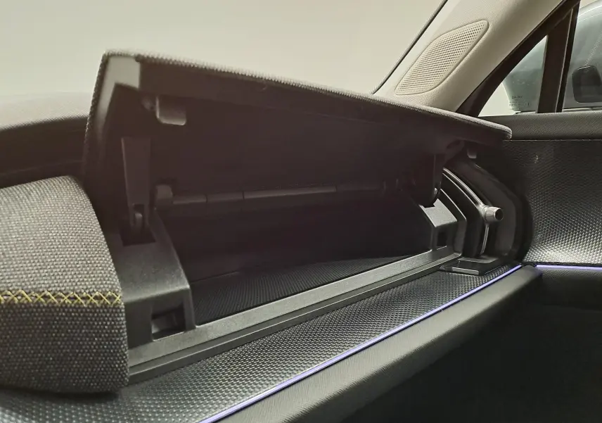Vue intérieure du coffre à gants ouvert côté passager du Skoda Kodiaq 2025 avec finition tissu et éclairage d'ambiance violet.