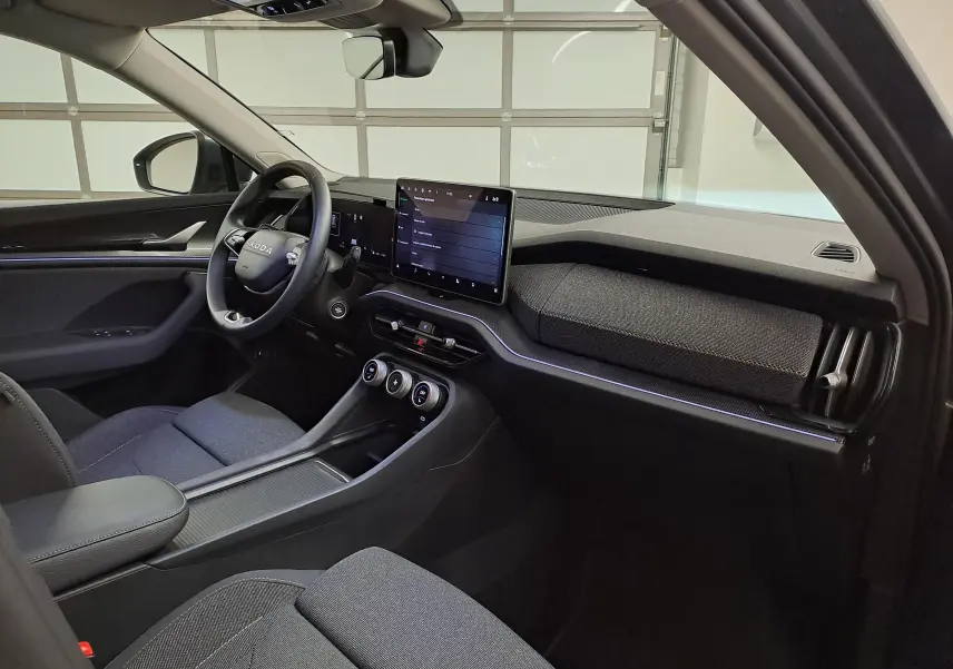 Vue intérieure côté conducteur du Skoda Kodiaq 2025, tableau de bord moderne avec écran tactile et finitions tissu gris.