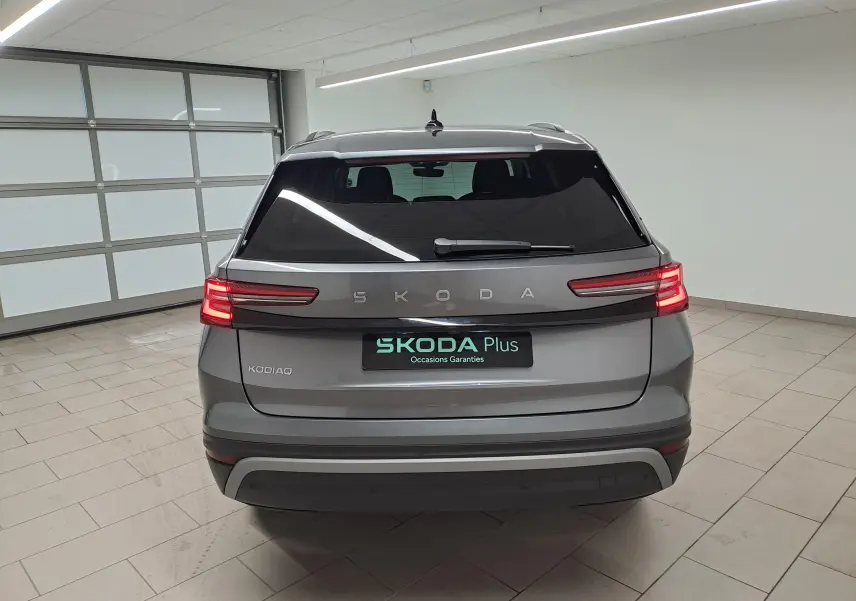 Vue arrière d'un Skoda Kodiaq gris graphite 2025 avec vitres surteintées et feux arrière allumés en intérieur.