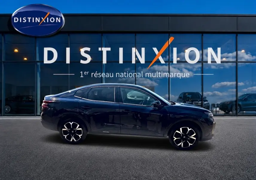 Vue de profil côté gauche d'une Citroën C4 X bleu foncé avec jantes alu devant une vitrine Distinxion.