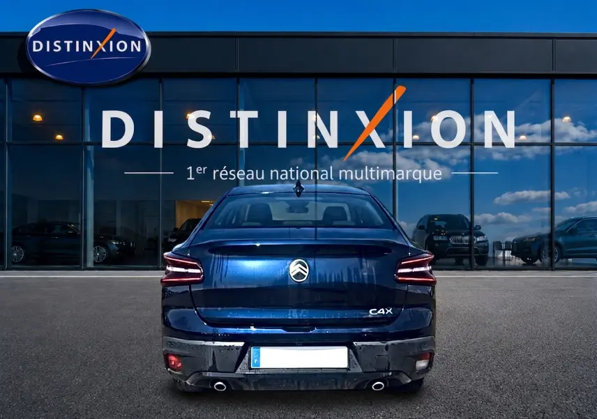 Vue arrière d'une Citroën C4 X bleu 2025 avec feux LED et double sortie d'échappement, devant une vitrine Distinxion.