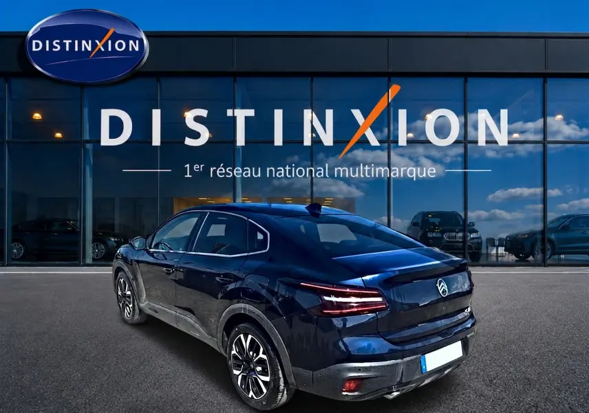 Vue 3/4 arrière droite d'une Citroën C4 X bleu foncé garée devant une concession Distinxion.