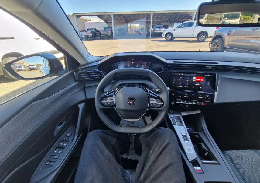 Vue intérieure centrée sur le volant et le tableau de bord de la Peugeot 308 gris Artense avec écran tactile et commandes au volant.