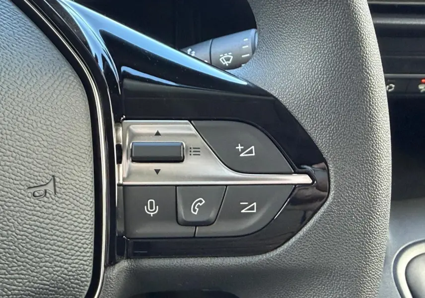 Gros plan sur les commandes multifonctions noires et argentées du volant du Peugeot Partner blanc Icy 2026.