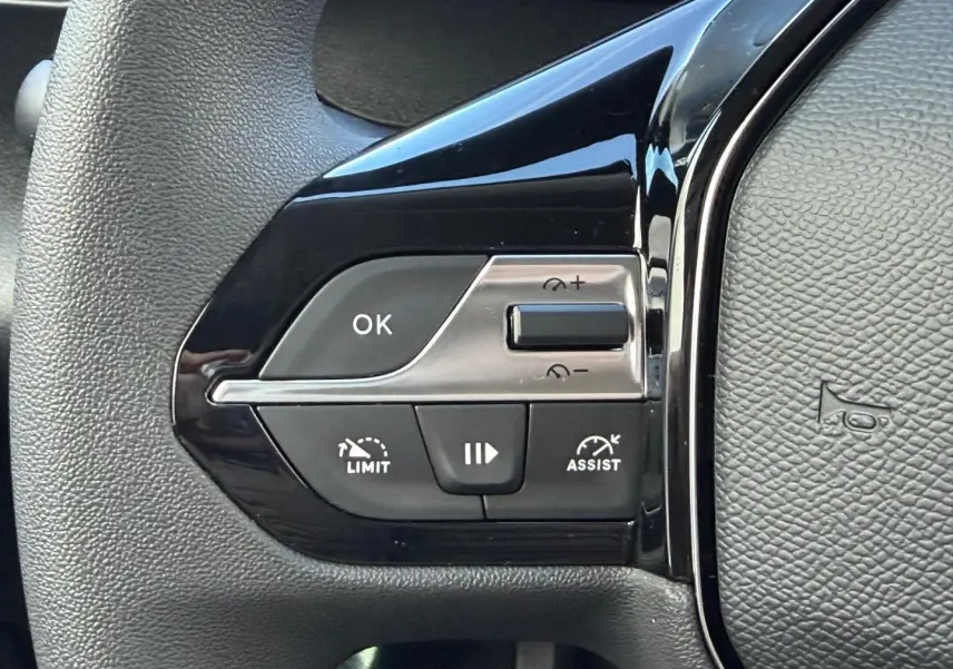 Gros plan sur les commandes de régulateur de vitesse au volant noir du Peugeot Partner blanc Icy 2026.